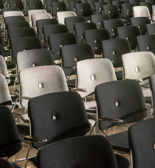 Rows of black and gray chairs in an auditorium, showcasing comfort and style.